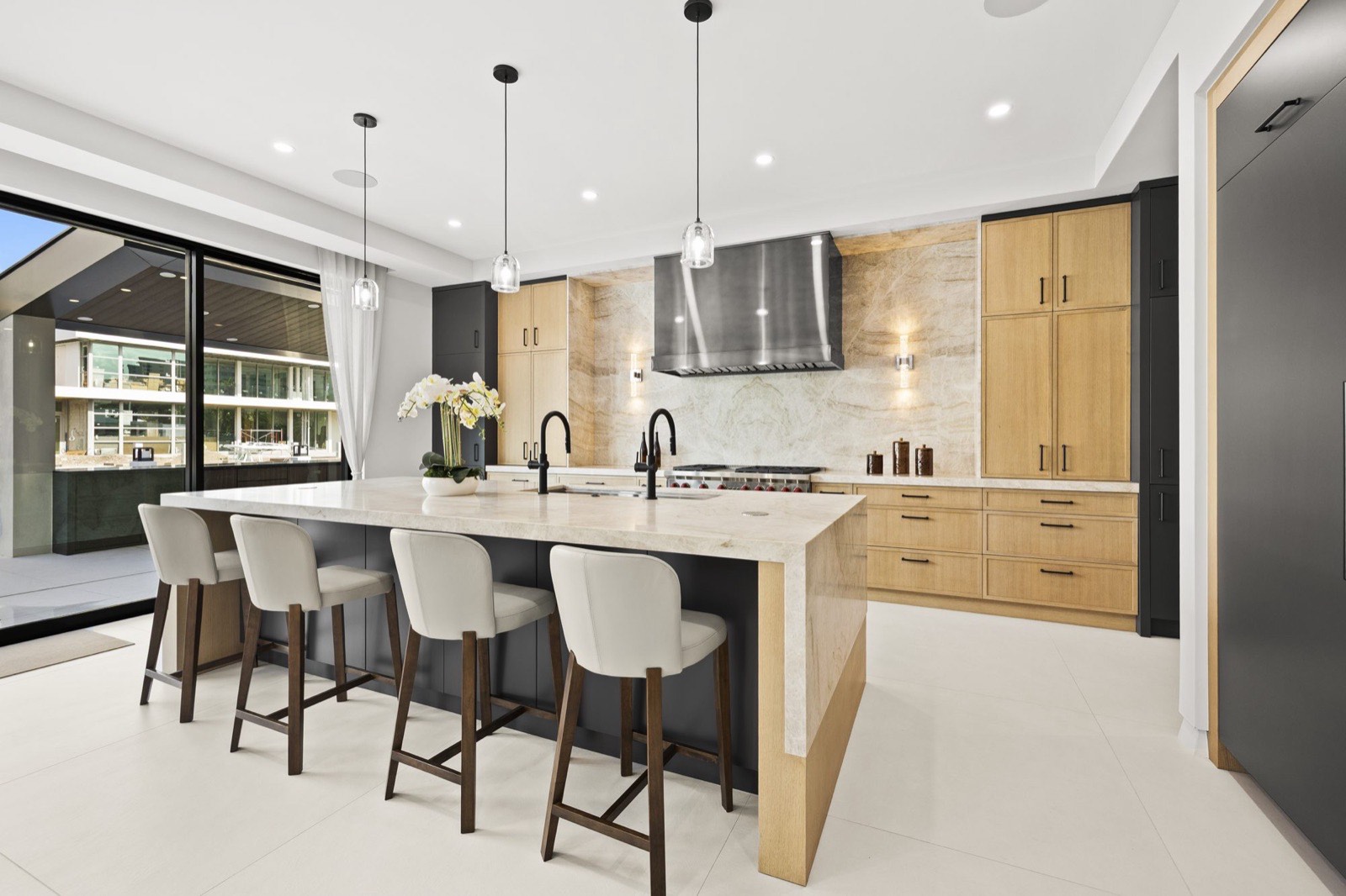 Kitchen with waterfall stone island, oak cabinetry, and pendant lighting