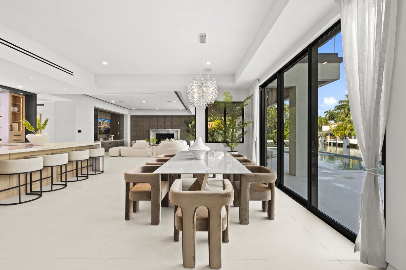 Open dining and living room with floor-to-ceiling glass opening onto the pool terrace